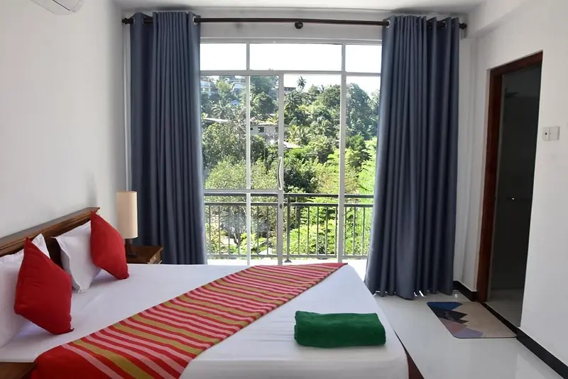 Double room with red cushions and a big window onto forested hills