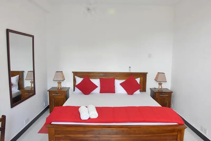 Double bed with red throw and a tall mirror