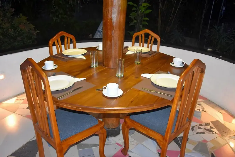 Round teak breakfast table and chairs laid with cups and plates on the terrace